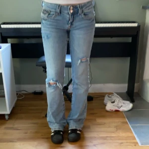 Blå jeans från Gina Tricot - Säljer ett par snygga blå jeans från Gina Tricot i storlek 164. Jag har gjort hålen själv. Jeansen är i bootcut-stil och har en låg midja. Använda fåtal gånger!❤️