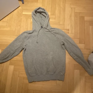 Grå hoodie från h&m - Säljer en klassisk grå hoodie från H&m. Den har en bekväm passform med långa ärmar och en praktisk huva med dragsko. Perfekt för en avslappnad stil.