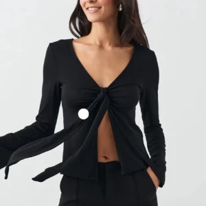 Svart topp - Snygg topp från Gina med knyte vid bröstet, lite nopprig men fint skick