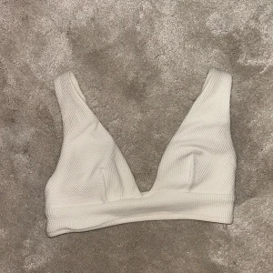 Vit ribbad bikiniöverdel - Snygg vit bikiniöverdel med ribbad textur och justerbara axelband. Perfekt för en stilren look på stranden eller vid poolen. Enkel och bekväm design som passar till det mesta.