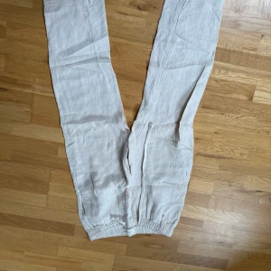 Beige linnebyxor från A Day's March - Snygga beige linnebyxor från A Day's March med elastisk midja och snörning. Perfekta för en avslappnad stil. Byxorna har en luftig passform och är tillverkade i ett lätt och bekvämt material.