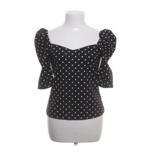 Svart prickig topp - Snygg svart topp med vita prickar och trekvartsärm. Toppen har en söt hjärtformad urringning och puffiga ärmar. Super bra skick, säljer eftersom den tyvärr aldrig kommer till användning. Storlek:S