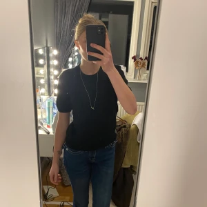 Svart kortärmad tröja - Säljer en stilren svart tröja med korta ärmar. Perfekt för en minimalistisk look. Tröjan har en rund hals och är gjord i ett mjukt material.