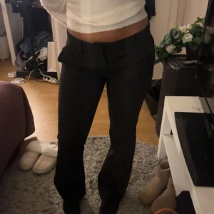 Svarta kostymbyxor - Snygga svarta kostymbyxor med en klassisk design. De har en rak passform och är perfekta för en stilren look. Byxorna har knappar och dragkedja framtill.