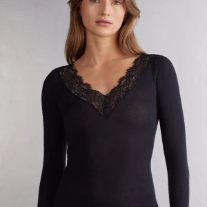 Ultralight lång blus i modalkashmir och spets från intimissimi  - Ultralight lång blus i modalkashmir och spets från intimissimi. Elegant svart långärmad topp med v-ringning och spetsdetaljer vid hals och ärmslut. Knappt använd och nypris ligger på 459 kr. Supertrendig topp! 💞