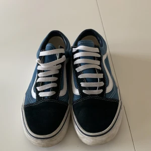 Blå och marinblå sneakers från Vans - Snygga blå och marinblå sneakers från Vans med vit sula och klassisk vågig sidodetalj. Skorna har vita snören och en gummisula med bra grepp. Perfekta för en avslappnad stil.