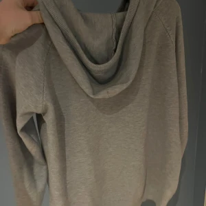 Grå Merinoull hoodie - Säljer en stilren grå hoodie med långa ärmar och justerbar huva. Perfekt för en avslappnad look. Den är mjuk och bekväm, idealisk för kyligare dagar. pris kan diskuteras vid snabb affär