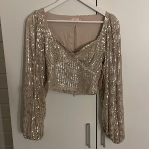 Festtopp - Säljer en champagnefärgad topp från Nelly med paljetter💞Toppen är endast testad och är i nyskick med prislapp kvar då den inte passade mig, köptes för 349kr!
