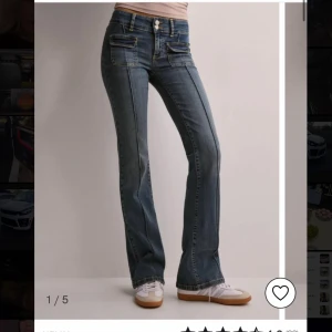 Blå bootcut jeans från Nelly - Snygga blå bootcut jeans från Nelly med en klassisk femficksdesign. Jeansen har en smickrande passform och är perfekta för en avslappnad stil. De har en dragkedja och knapp framtill.