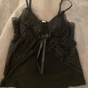 Svart spetslinne med rosett - Jättefint linne/pyjamaslinne som tyvärr är för litet för mig, men bara använd kanske 4 gånger så den är i väldigt bra skick! Linnet är lite vadderat på insidan. Jättefin men passar mig tyvärr inte.