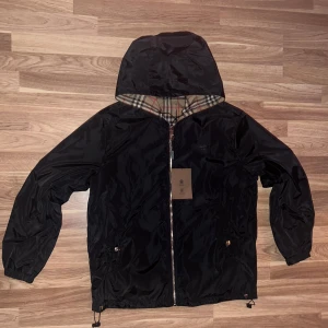 Burberry vindjacka - Säljer en stilren svart vindjacka från Burberry som man kan vända ut och in. Ny skick, storlek XL men passar mer som L/M. Skriv om funderingar eller frågor!