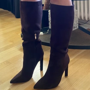 Bruna stövlar med klack - Snygga bruna stövlar i mocka med spetsig tå och hög klack. De har en dragkedja på sidan för enkel på- och avtagning. Perfekta för att ge en elegant touch till din outfit. Använda en gång utomhus men då klacken (ca 10cm) är lite hög för min smak så säljer jag💖