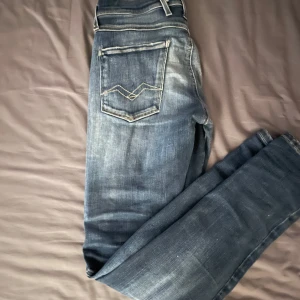 Blåa Replay jeans - Snygga blå jeansbyxor från Replay i modellen Anbass. De har snygga slitningar och broderade bakfickor. Skitsnygga passar till allt. Hålen är lappade och kan skicka närbild vid förfrågan. Dom är i storlek W28 L32. Skriv vid funderingar 