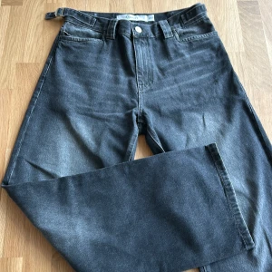 Grå jeans från Vicinity - Säljer ett par snygga grå jeans från Vicinity i storlek M. De har en bredare passform och en cool logga på baksidan. Jeansen är i väldigt bra skick/inga defekter! Använd få gånger och säljer då jag har bytt stil.