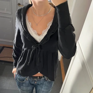 Svart knyttröja - Svart tröja med knytning och volanger från House of Lola i storlek S. Fint skick. Använd gärna köp nu!