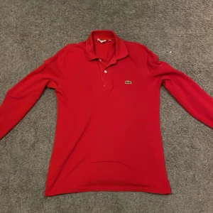 Röd pikétröja från Lacoste - Säljer en klassisk röd pikétröja från Lacoste i mycket bra skick. Tröjan har långa ärmar och den ikoniska krokodilloggan på bröstet. Perfekt för både vardag och lite finare tillfällen. Passar bra till jeans.Nypris runt 1500kr.Den är i bra skick och jag har knappt använt den.Storlek S