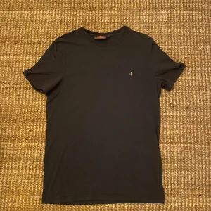 Morris t-shirt - Säljer en stilren mörkblå t-shirt från morris i mycket bra skick. Den har en liten broderad logga på bröstet och är gjord i mjukt bomullsmaterial. Perfekt för både vardag och fest! Aldrig använt t-shirten!
