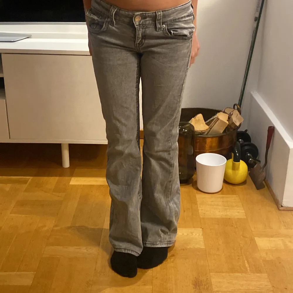 Säljer ett par snygga grå bootcut jeans i bra skick. De är lågmidjade och har en klassisk femficksdesign med knappar och dragkedja fram. Perfekta för både vardag och fest! 🖤. Jeans & Byxor.