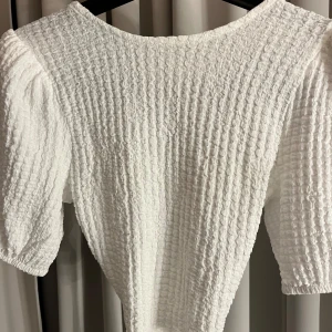 Vit topp med knyt - Vit topp med korta ärmar och öppen rygg med knytning. Använd 1 gång, super bra skick. Pris kan diskuteras🩷