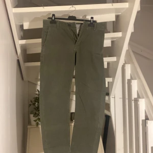 Gröna chinos från Dockers - Säljer ett par snygga gröna chinos från Dockers i modellen Alpha Khaki. De har en klassisk design med fickor både fram och bak, och är perfekta för både vardag och lite mer uppklädda tillfällen. Byxorna är i bra skick och har en normal passform. Perfekta för höst och vår! SLIM!
