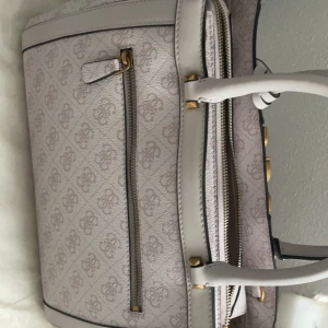Guess väska  - Säljer en äkta Guess väska, köptes i polen.  Helt ny, köptes för 699 polska pengar, det blir 2012,59kr i svenska, säljer för 1,900. Priset kan diskuteras.