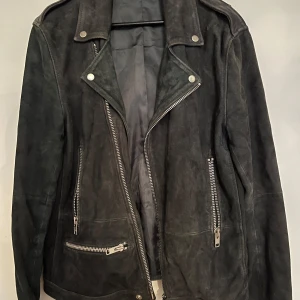 Svart mockajacka från Samsøe Samsøe - Säljer en snygg svart mockajacka från Samsøe Samsøe. Jackan har en klassisk bikerstil med dragkedjor och knappar i silver. Den är långärmad och har en cool, edgy look. Perfekt för höst och vår!