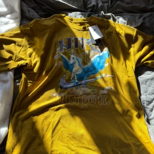 Gul t-shirt med Pegasus-tryck från Nike - Köpt på Junkyard och endast testad en gång. Säljes pga att den var för stor. Storlek medium oversize men skulle säga att det är en xl-xxl.