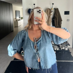 Jeans topp - Helt oanvänd jeans topp med knyt framtill och puffärmar från Ginatricot. 