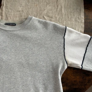 Ljusgrå Brandy Melville Tröja - Mysig och mjuk tjocktröja från Brandy melville i ljusgrått med en vit panel på varje arm.  Storlek är onesize och är lite för liten för mig (172 cm)