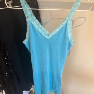 Blå linnetopp från Hollister - Säljer en superfin blå linnetopp från Hollister. Den har spetsdetaljer vid axelbanden och en v-ringad design. Jätta fint skick. Säljer då den inte kommer till användning! 