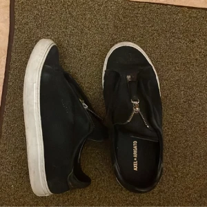 Svarta sneakers från Axel Arigato - Säljer ett par svarta sneakers från Axel Arigato, mocka. Köpta på Plick därför är de ganska använda därav priset. Säljer pågrund av att de inte passar mig längre