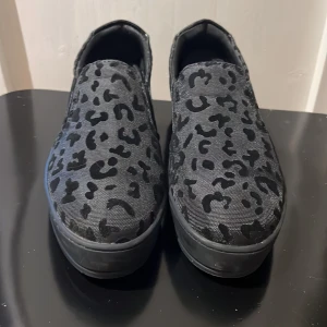 Svarta sneakers med leopardmönster - Säljer ett par svarta sneakers från Attitude med leopardmönster. Skorna är tillverkade i syntetmaterial. Sköna och oanvända skor i storlek 37.