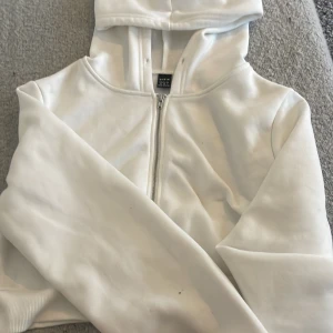 Vit croppad hoodie med dragkedja från SHEIN - Säljer en vit croppad hoodie från SHEIN i storlek xs. Tröjan har dragkedja framtill, huva och långa ärmar. Perfekt för en avslappnad och trendig stil. Materialet är mjukt och bekvämt.💕 