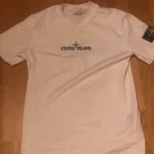 Vit t-shirt från Stone Island - Vit t-shirt från Stone Island med tryckt logga på bröstet, helt ny och aldrig använd. Säljer för den var för liten. Kom med bud men inget under 250.