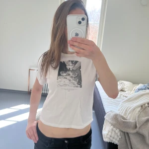 Vit t-shirt med svartvitt tryck - Vit t-shirt med svartvitt tryck framtill som föreställer staplade champagneglas. T-shirten har rund halsringning och korta ärmar. 