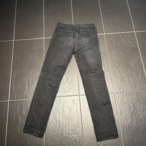 Svarta arket jeansbyxor med rak passform - Säljer ett par svarta jeansbyxor med klassisk femficksdesign och rak passform. Byxorna har normal midja och stängs med dragkedja och knapp. Perfekta för en stilren och enkel look.