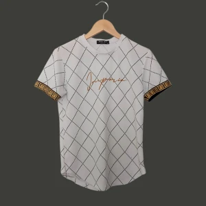 Vit t-shirt med svart rutmönster och gulddetaljer från Janny Wolf - Vit t-shirt med svart rutigt mönster och guldfärgad text 'Imperio' på bröstet. Ärmarna har en snygg guldfärgad grekisk bård. T-shirten har rund hals och är tillverkad i ett strukturerat material.