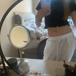 Svart ribbad croppad topp från NA-KD - Säljer en svart ribbad croppad topp från NA-KD med korta ärmar och volangkant nedtill. Toppen har en rund halsringning och är tillverkad i ett mjukt material som sitter bekvämt på kroppen. Perfekt för en trendig och avslappnad stil. Använd några gånger men inte sliten eller söndrig någonstans