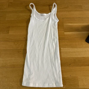 Vit ribbad linnetopp - Säljer en klassisk vit ribbad linnetopp i stretchigt material. Storlek XS och köpt utomlands. Perfekt att bära som lager eller för sig själv. Tidlös modell med rund halsringning och smala axelband. Finns en liten defekt som syns i andra bilden, därav priset! Sparsamt använd!