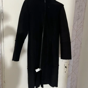 Svart lång kappa från Vero Moda - Säljer en svart lång kappa från Vero Moda i storlek medium. Jackan har lång ärm och stängs med dragkedja framtill. Perfekt för dig som gillar en stilren och enkel look.