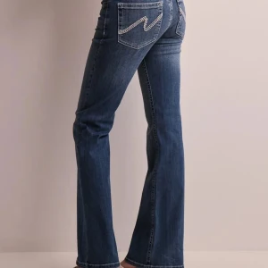 Blå bootcut jeans med broderade bakfickor från Nelly💓 - Snygga blå jeans med bootcut passform och broderade detaljer på bakfickorna. Klassisk femficksmodell med normal passning och dragkedja. Perfekta för en avslappnad och trendig look.