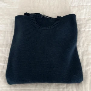 Mörkblå stickad tröja från Brandy Melville - Säljer en mörkblå stickad tröja från Brandy Melville. Tröjan har rund halsringning och långa ärmar med breda ribbade muddar vid ärmslut och nederkant. Tillverkad i 100% bomull för en mjuk och skön känsla.