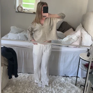 Beige croppad stickad tröja med krage - Säljer en beige croppad stickad tröja med v-ringning och krage. Tröjan har långa ärmar och en avslappnad passform, perfekt för en chill och stilren look.
