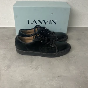 Svarta sneakers från Lanvin - Säljer ett par svarta sneakers från Lanvin med snygg kombination av skinn och mocka. Dem är lite använda men fortfarande i väldigt bra skick 8/10 det kommer till ett extra par skosnören från lanvin tveka inte att ställa någon fråga. Storlek 45 priset är ej hugget i sten