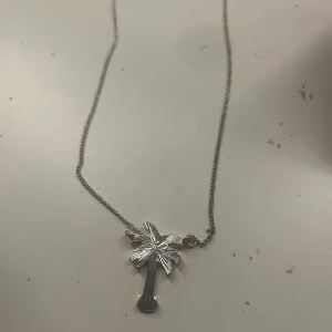 Silverfärgat halsband med palmberlock - Snyggt halsband i silverfärg med en detaljrik palmberlock. Perfekt accessoar för en somrig look eller för dig som gillar tropiska vibbar. Kedjan är tunn och smidig, och palmen ger ett unikt intryck.