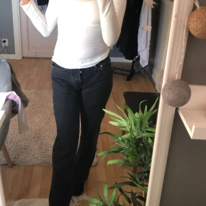 Svarta jeansbyxor med raka ben - Säljer ett par svarta jeansbyxor med raka ben och klassisk femficksdesign. Byxorna har medel midja och knäppning med knappar framtill. Perfekta för dig som gillar en enkel och tidlös stil. Byxorna är helt oandvända.