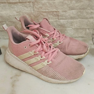 Rosa Adidas sneakers med mesh - Säljer ett par rosa Adidas sneakers med vit sula och klassiska tre ränder på sidan. Skorna har snörning och är tillverkade i meshmaterial som andas. Perfekta för vardagsbruk eller lätt träning. Sula behöver köpas till, då jag plockade ut den jag hade, och använde iläggsula