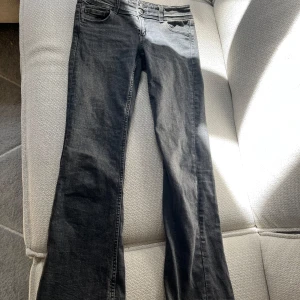 Svarta/grå bootcut jeans - Säljer ett par svarta/grå bootcut. Jeansen är utsvängda och lågmidjade och är endast använda fåtal gånger.
