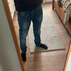Blå jeans från Jack's Sportswear - Säljer ett par klassiska blå jeans från Jack's Sportswear. Jeansen har normal passform, raka ben och snygga slitningar för en avslappnad look. Perfekta till vardags och passar till det mesta. Midjemått w30 och längd l30. Inte använda mycket 