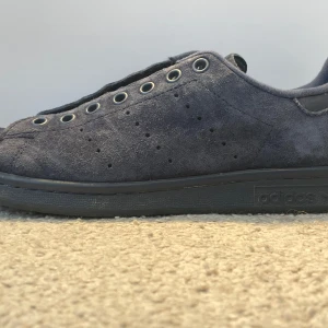 Mörkblå Adidas Stan Smith sneakers i mocka - Säljer ett par mörkblå Adidas Stan Smith sneakers i mjuk mocka. Skorna har klassisk låg profil, rund tå och platt sula. Ventilationshål på sidorna och metallfärgade öljetter för snörning. Perfekta för dig som gillar stilrena och tidlösa sneakers. Priset kan diskuteras eftersom skorna inte finns längre. Accepterar rimliga bud. Limited edition sko i mocka som inte säljs längre. Pris begagnat är cirka 1500 kr. Perfekta sommarskon för dig som vill stå ut. 